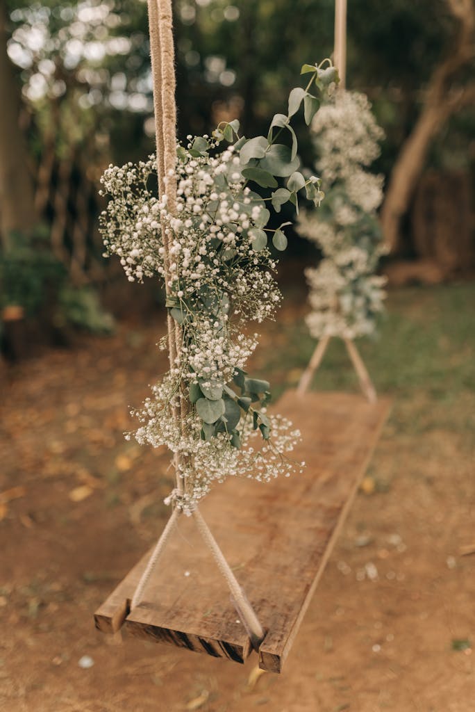 Wooden swing with baby's breath and eucalyptus flowers outdoors.